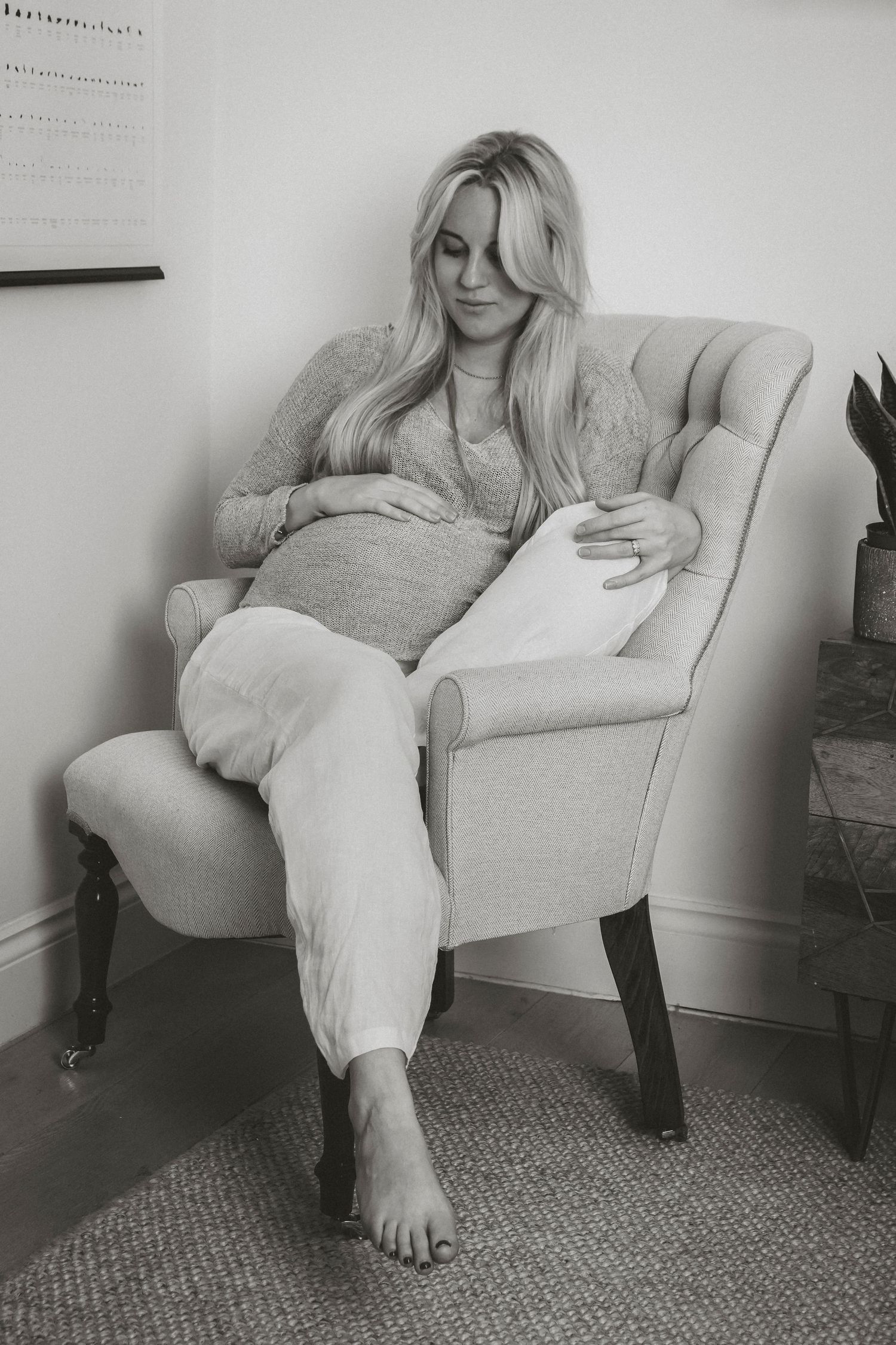 Black and white portrait of pregnant woman relaxing in cozy armchair, in Stoke Newington, London.