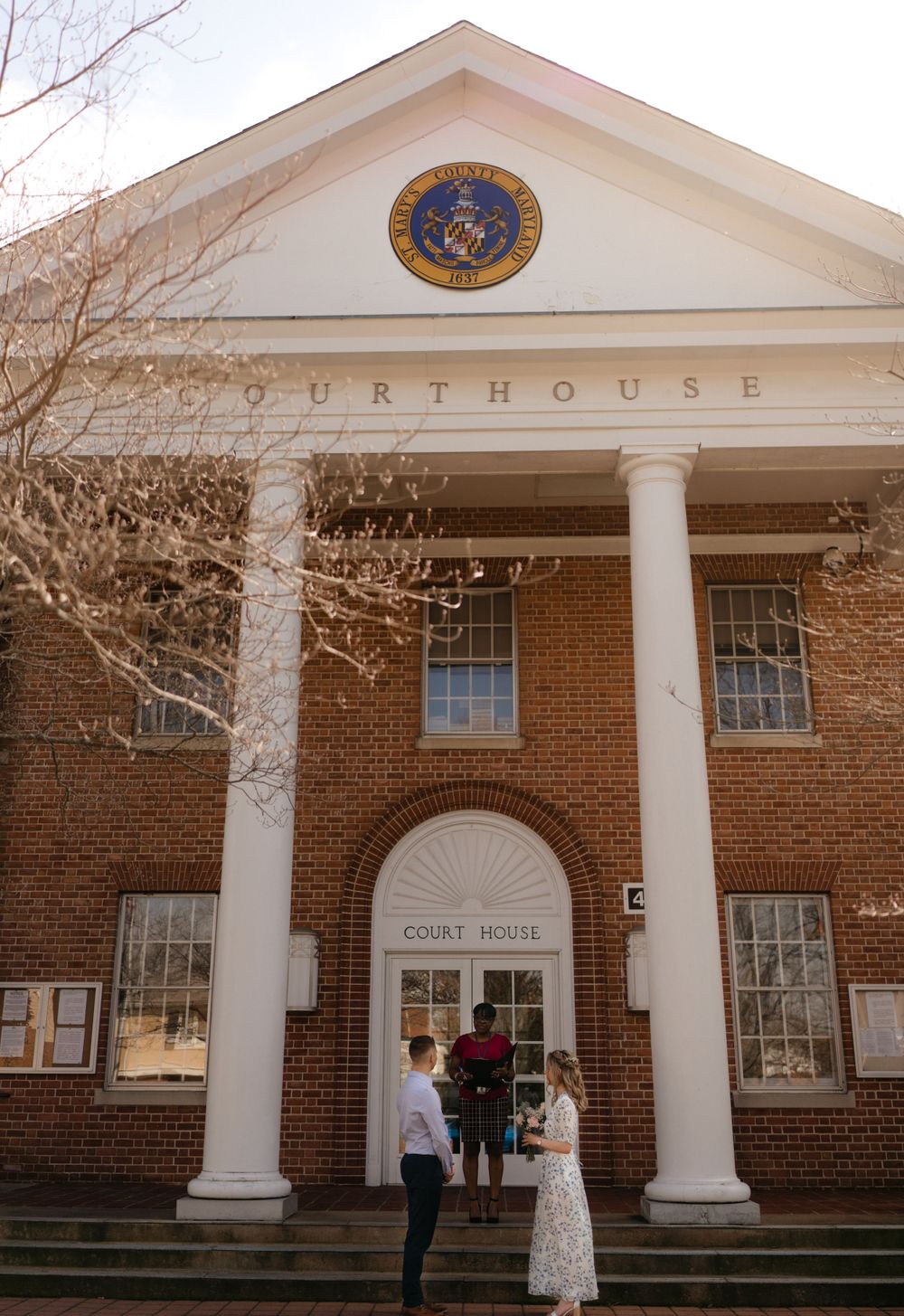 A classic brick courthouse entrance with white columns and a sunburst detail above the doorway.
