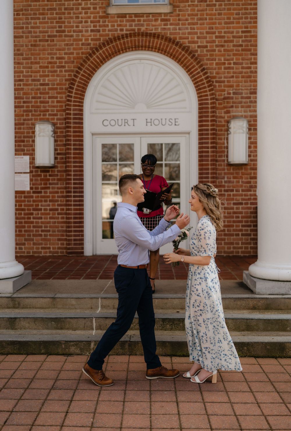 A courthouse wedding ceremony unfolding on the steps of a historic brick building.