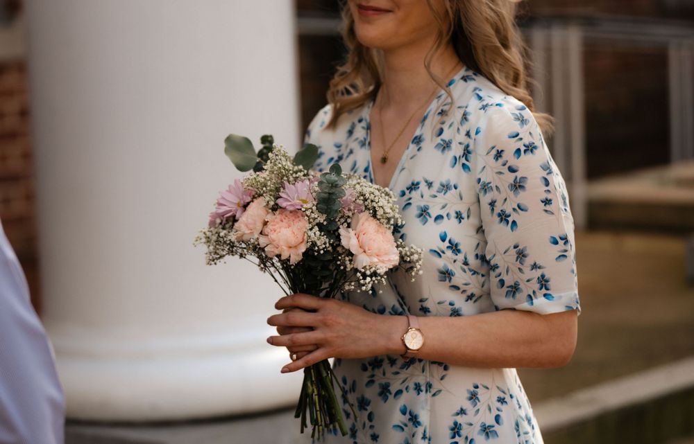 Close-up of a bouquet with pink roses and baby's breath against a floral dress.