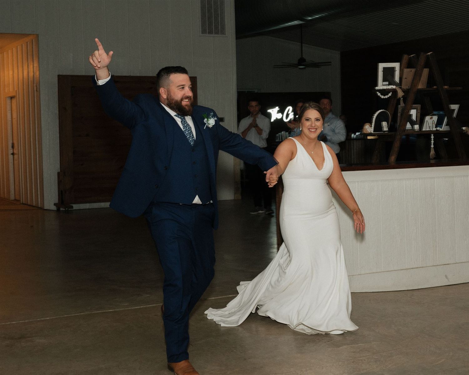 A couple in wedding attire makes their grand entrance dancing at their reception.