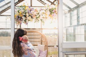 Bright and airy greenhouse venue decorated with romantic floral arrangements and delicate hanging lights for a wedding celebration.
