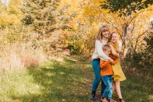 Siblings share a joyful moment together during an autumn photoshoot in a golden-lit outdoor setting.