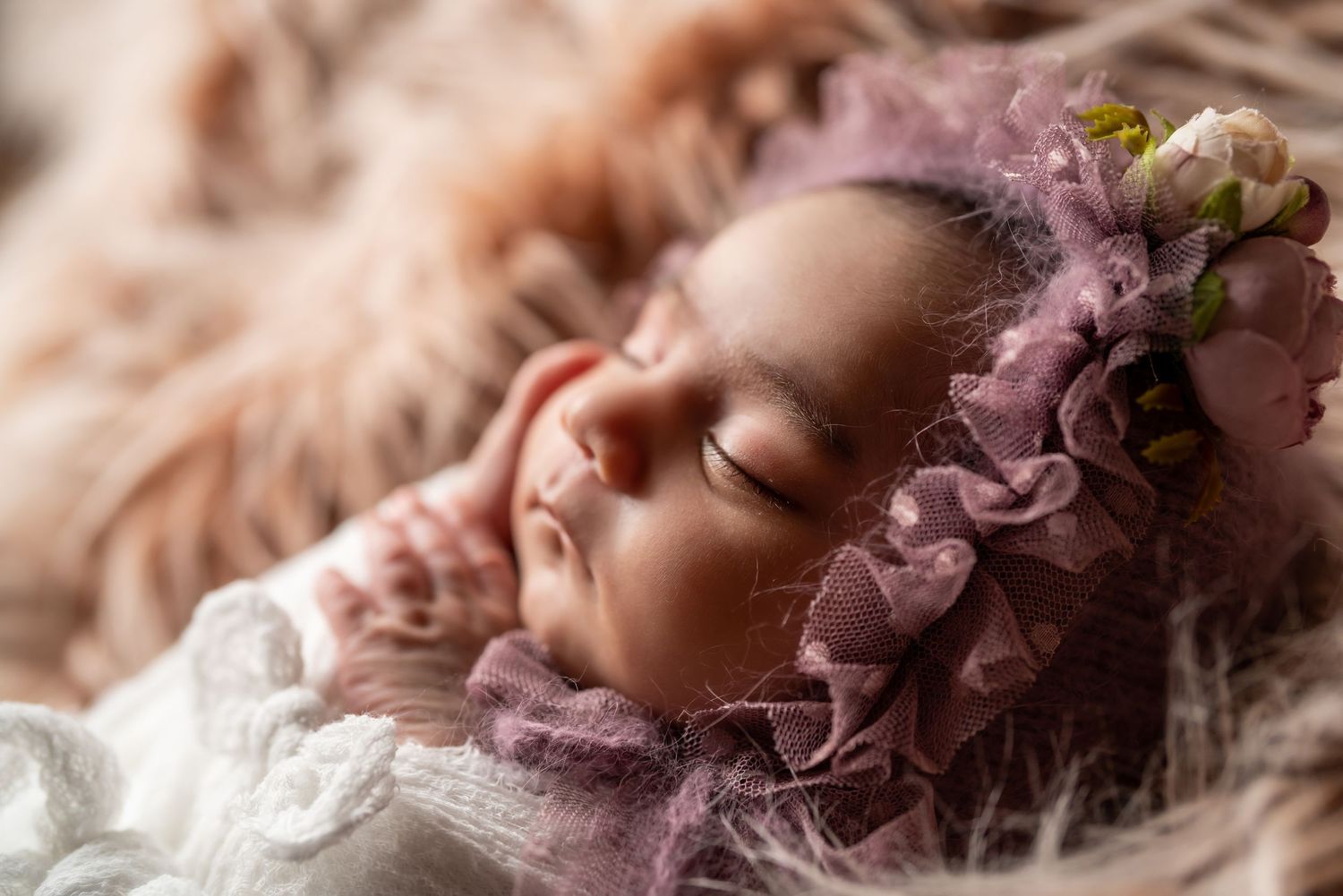 Dreamy newborn portrait with soft pink flowers and delicate lace details.