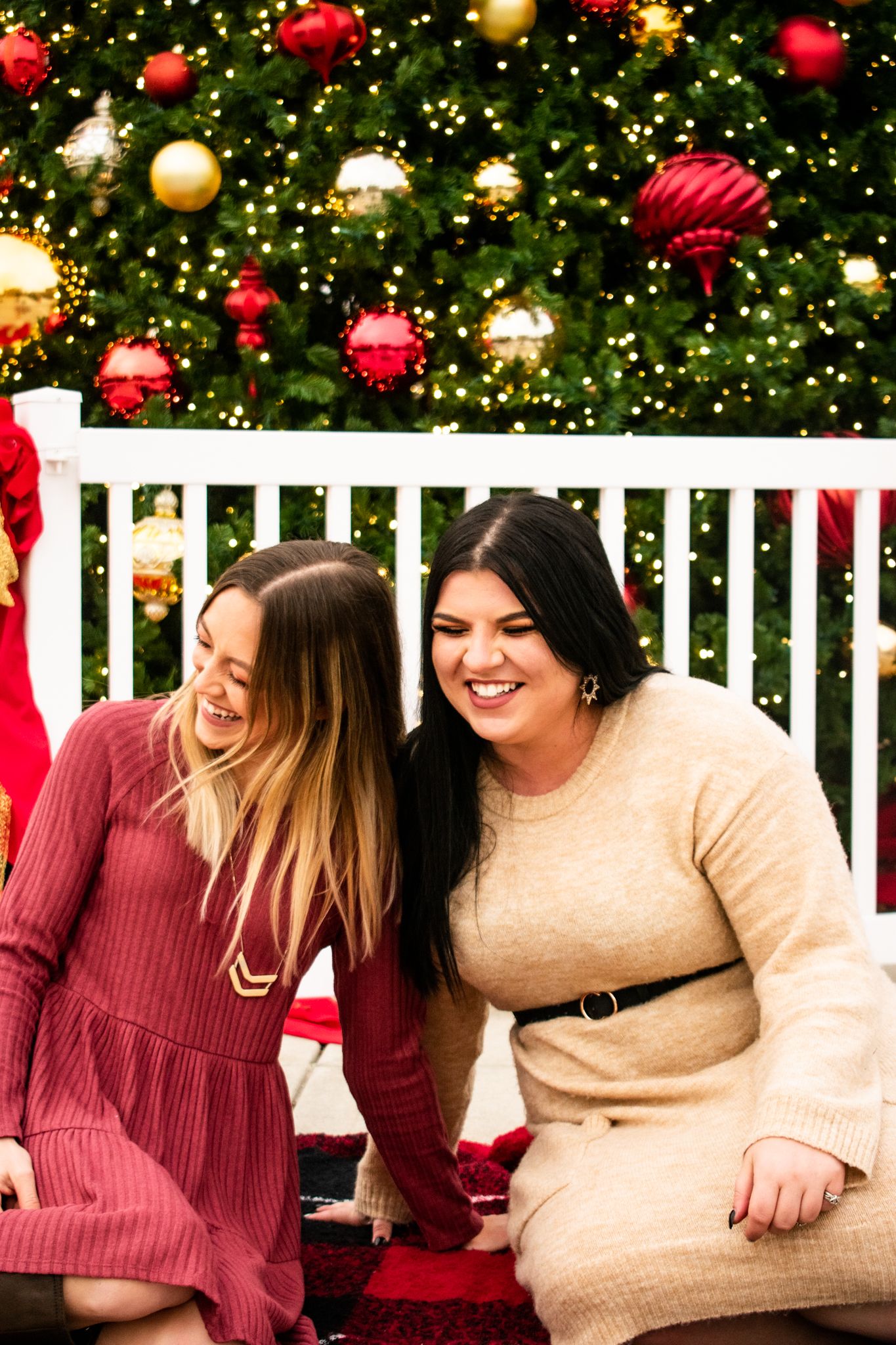 Candid moment of joy shared on white bench in front of decorated Christmas tree.