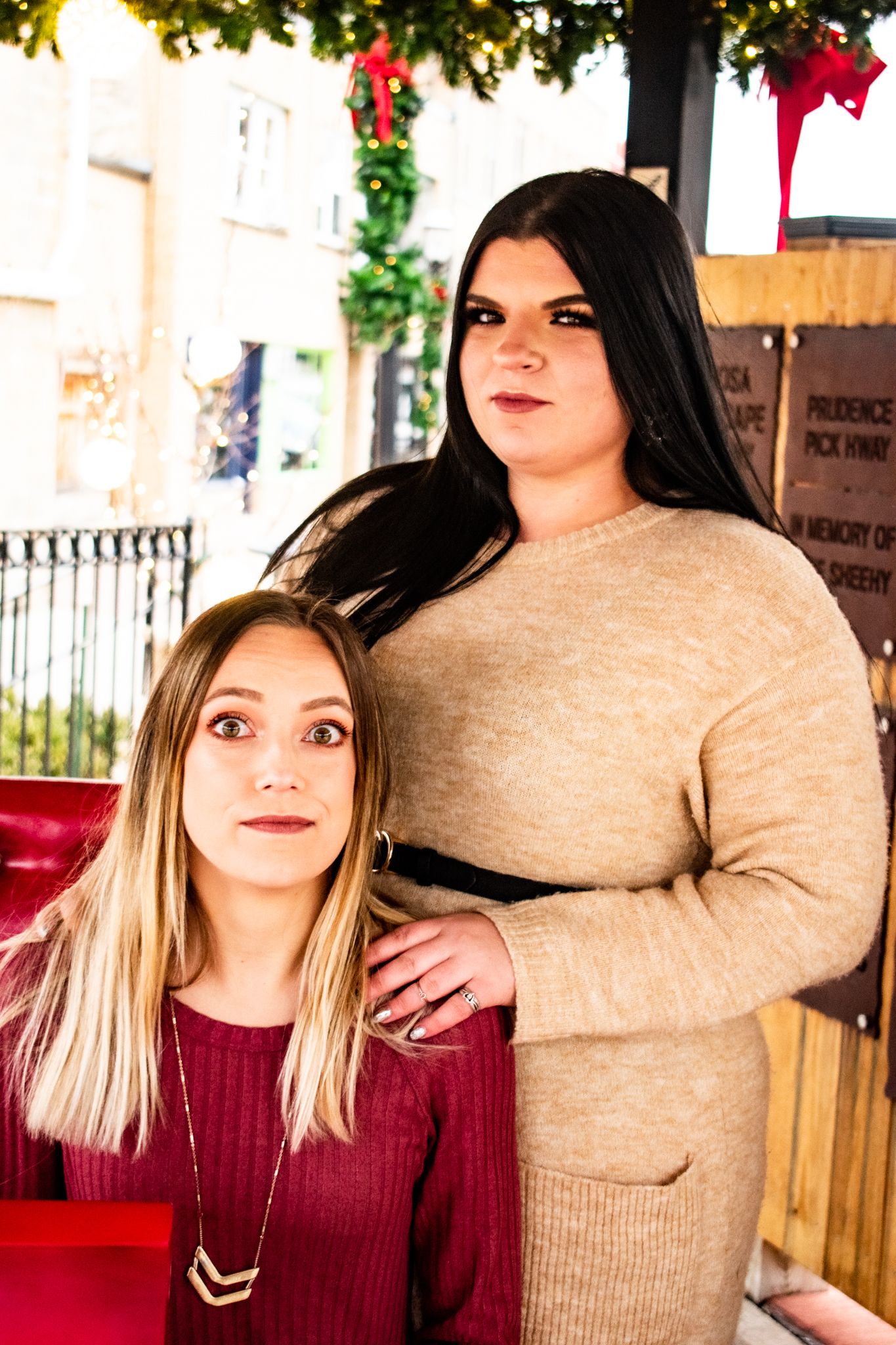 Friends in burgundy and beige outfits pose together on a red bench during holiday season.