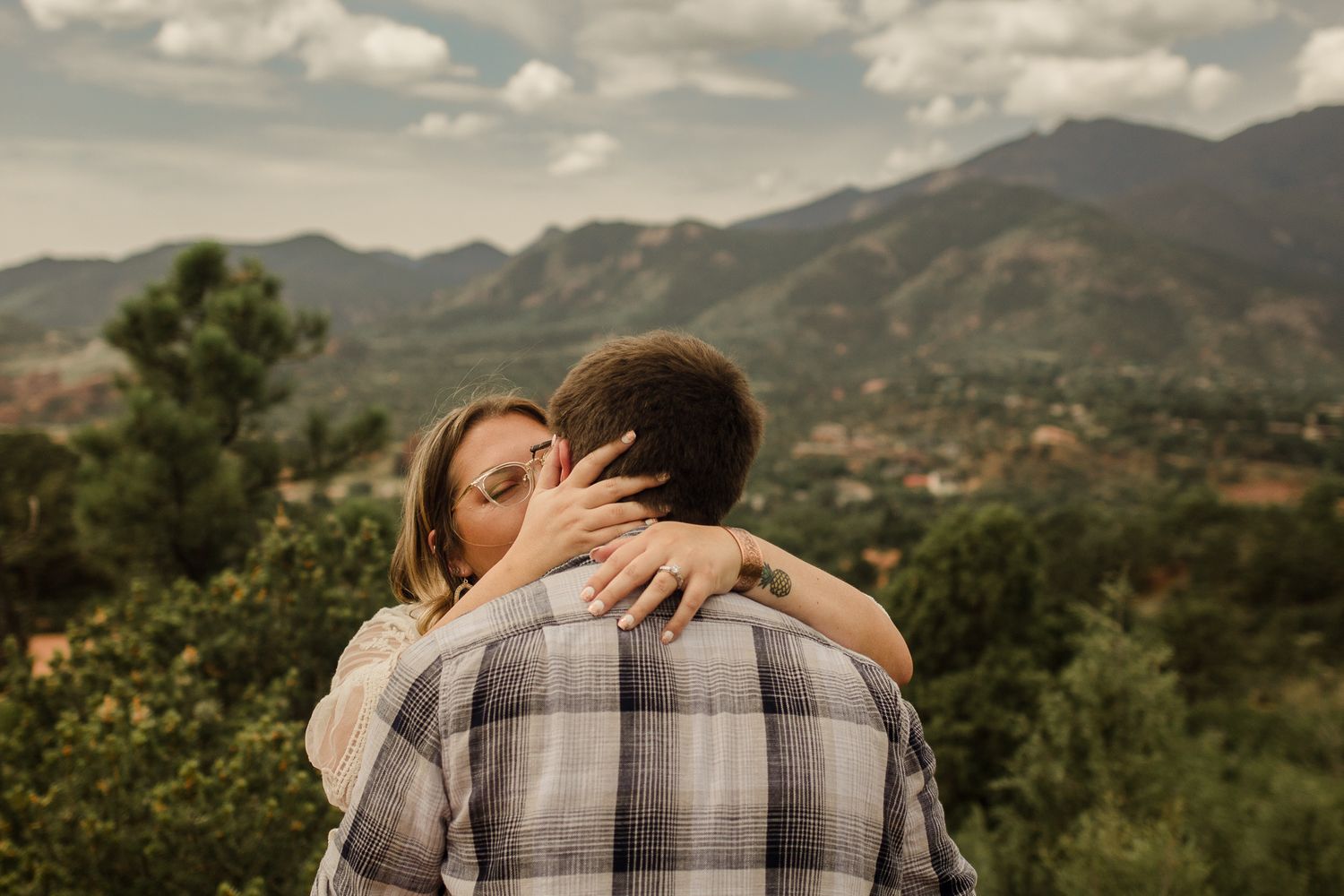 A couple embracing outdoors with mountains in background during golden hour.