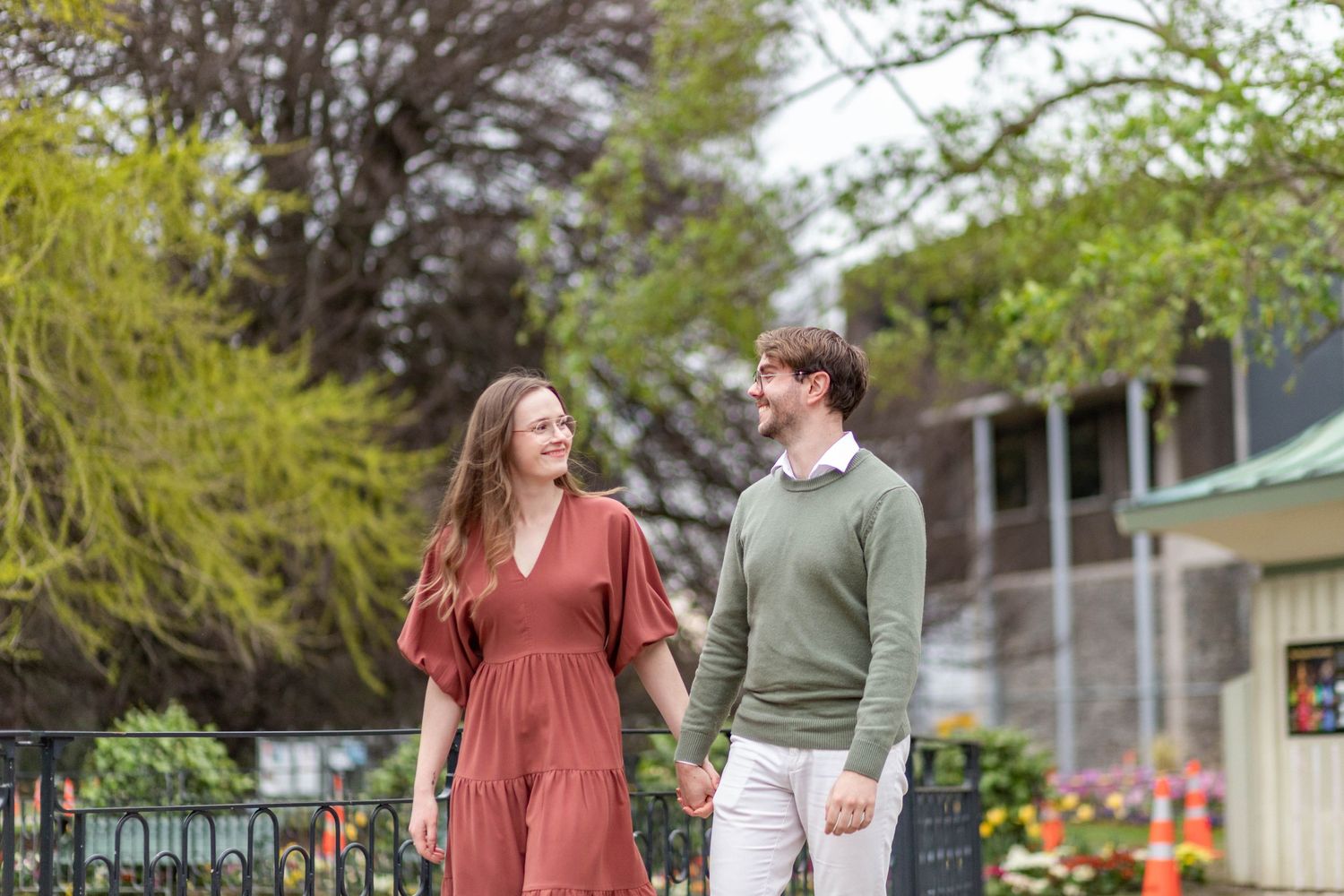 couple holding hands walking in a garden