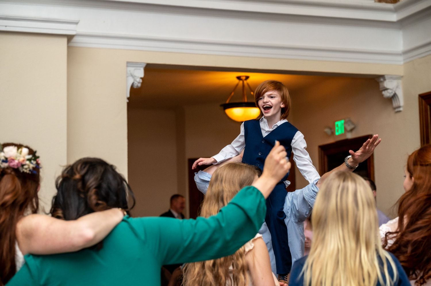 Wedding guests lift and celebrate during an energetic reception dance party.