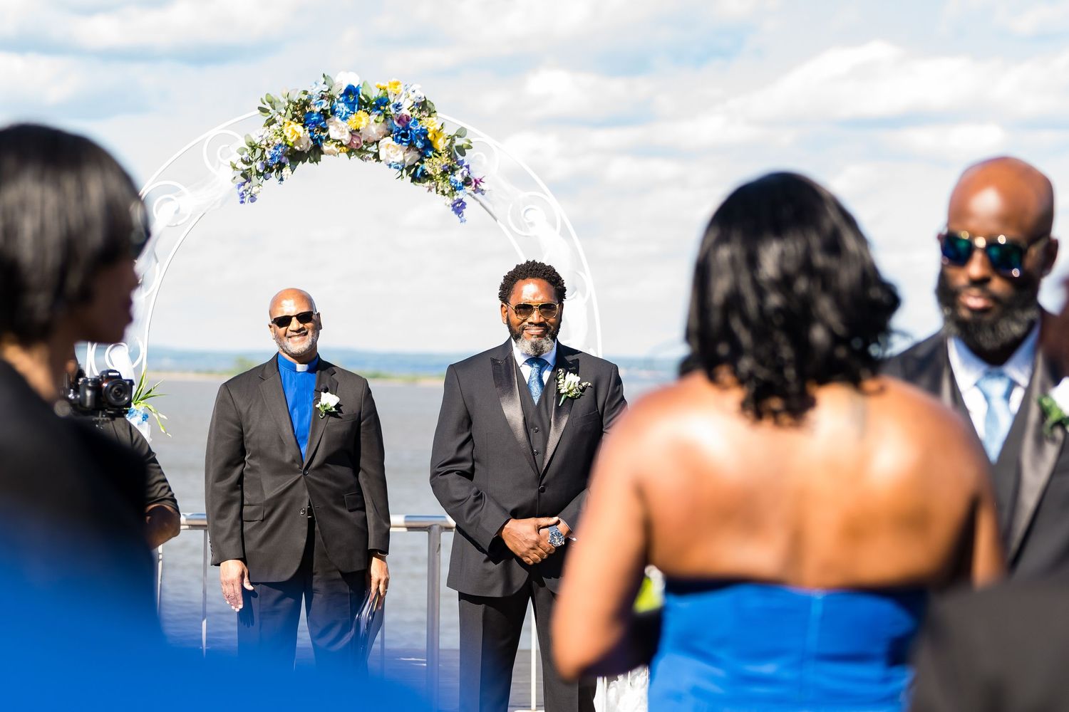 Outdoor wedding ceremony setup with floral arch against mountain backdrop.