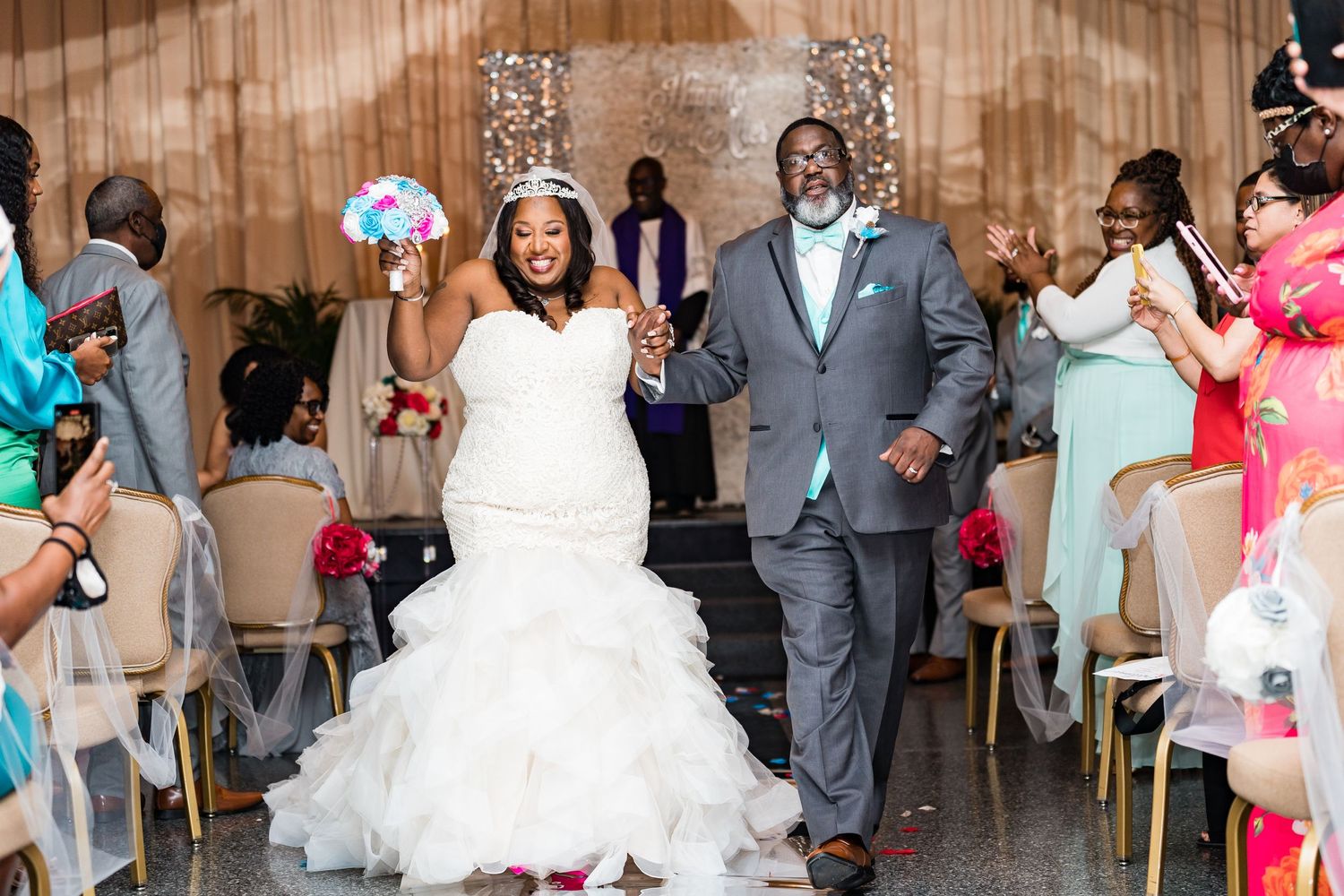 Joyful wedding recessional in decorated venue with guests celebrating.