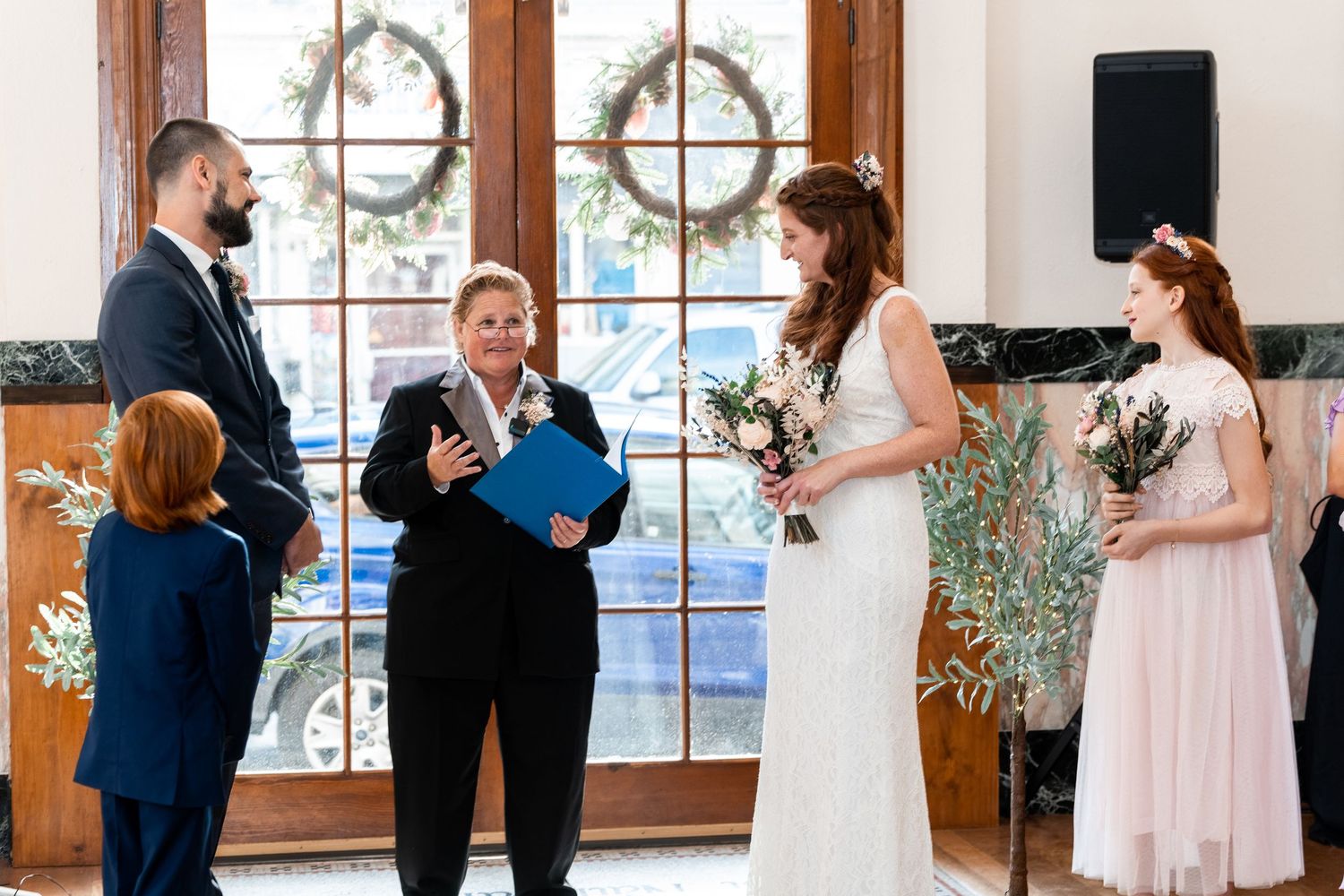 Intimate wedding ceremony in chapel with arched windows and natural lighting.