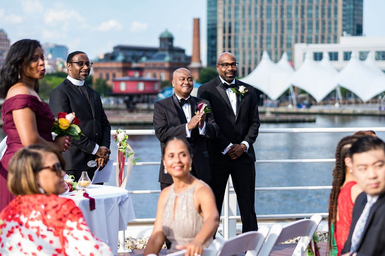 Outdoor waterfront wedding ceremony setup with city skyline in the background.