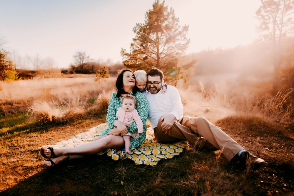 Candid family moment captured in a golden field at sunset.