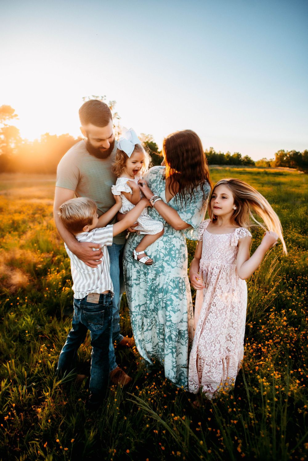 Joyful family interaction in a wildflower field during golden hour.