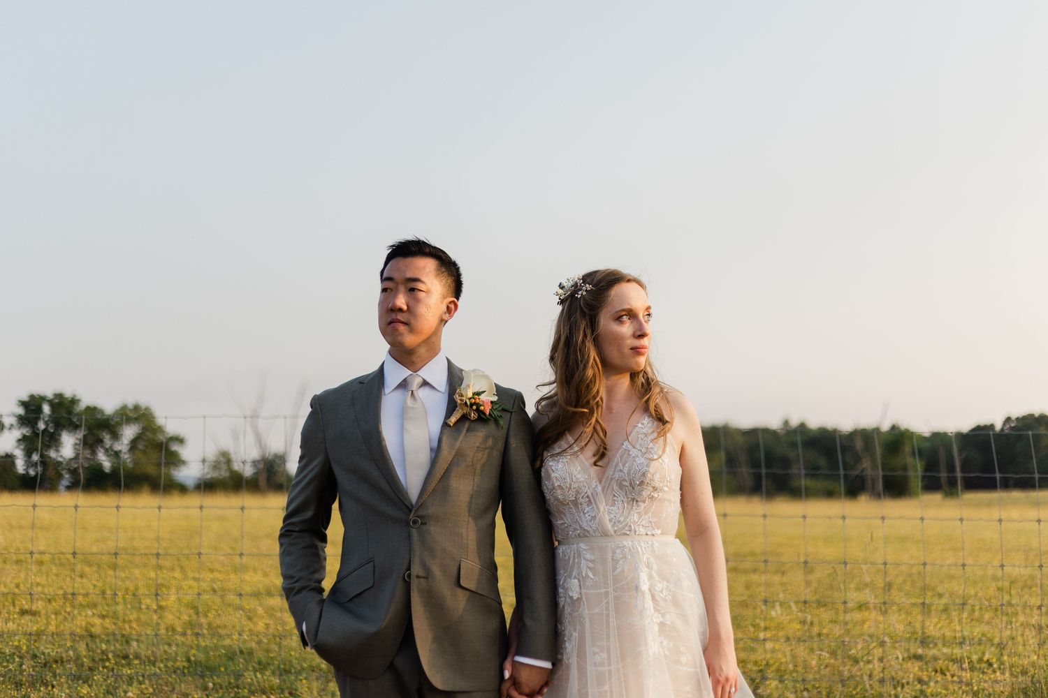 A newlywed couple poses in formal attire in a golden summer field. Puesta Del Sol Farm West Virginia WV Wedding