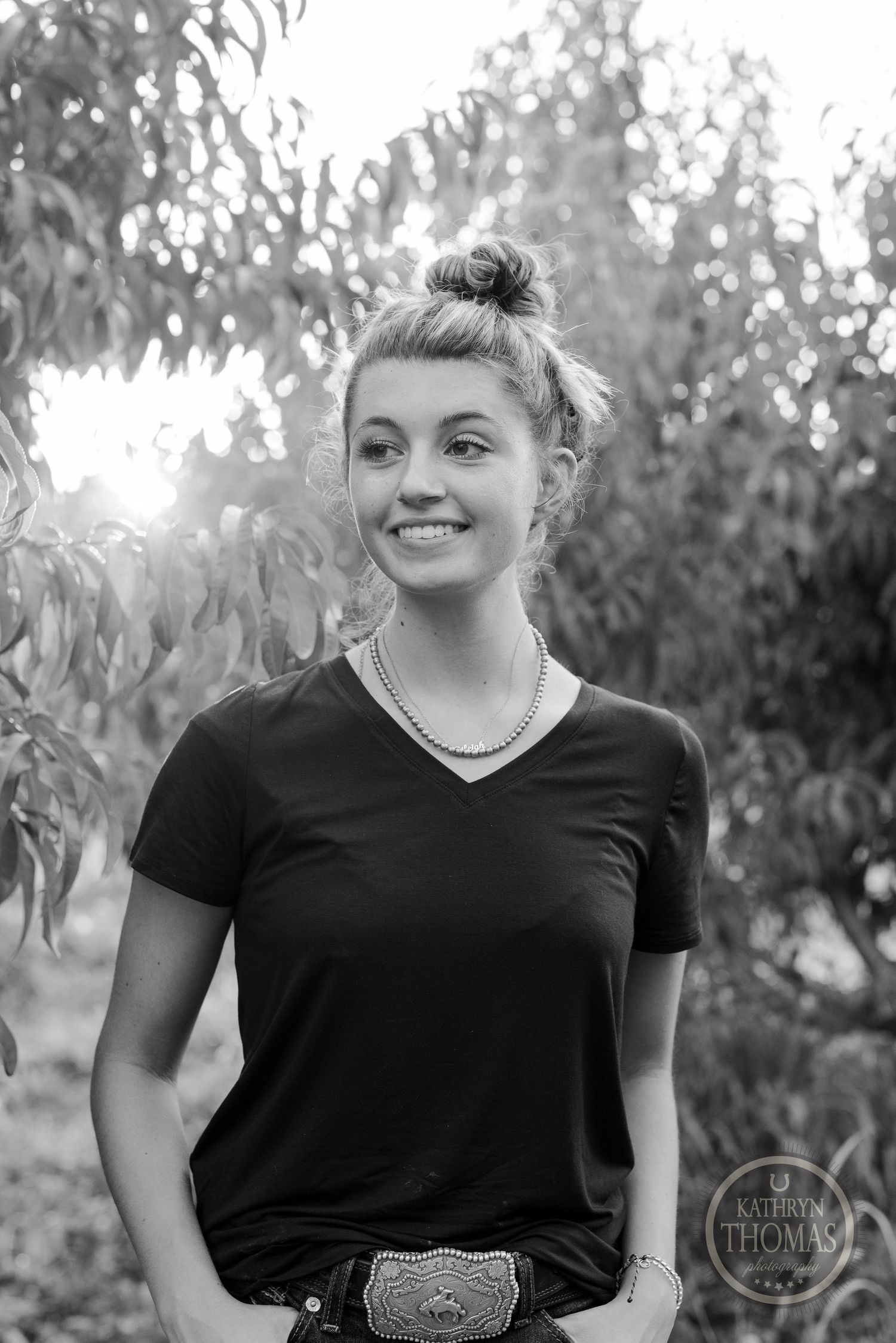 Black and white portrait in an orchard wearing casual attire and western belt.
