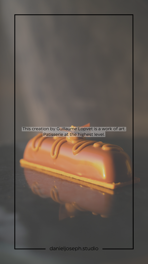 A glossy caramel-colored pastry bar with artistic chocolate detailing on a reflective surface.