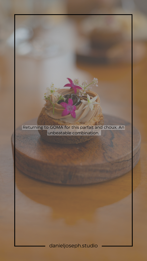 A delicate pastry topped with whipped cream and small purple flowers on a wooden stand.
