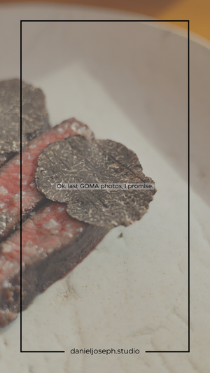 Close up of shaved black truffles garnishing a dish against a white background.