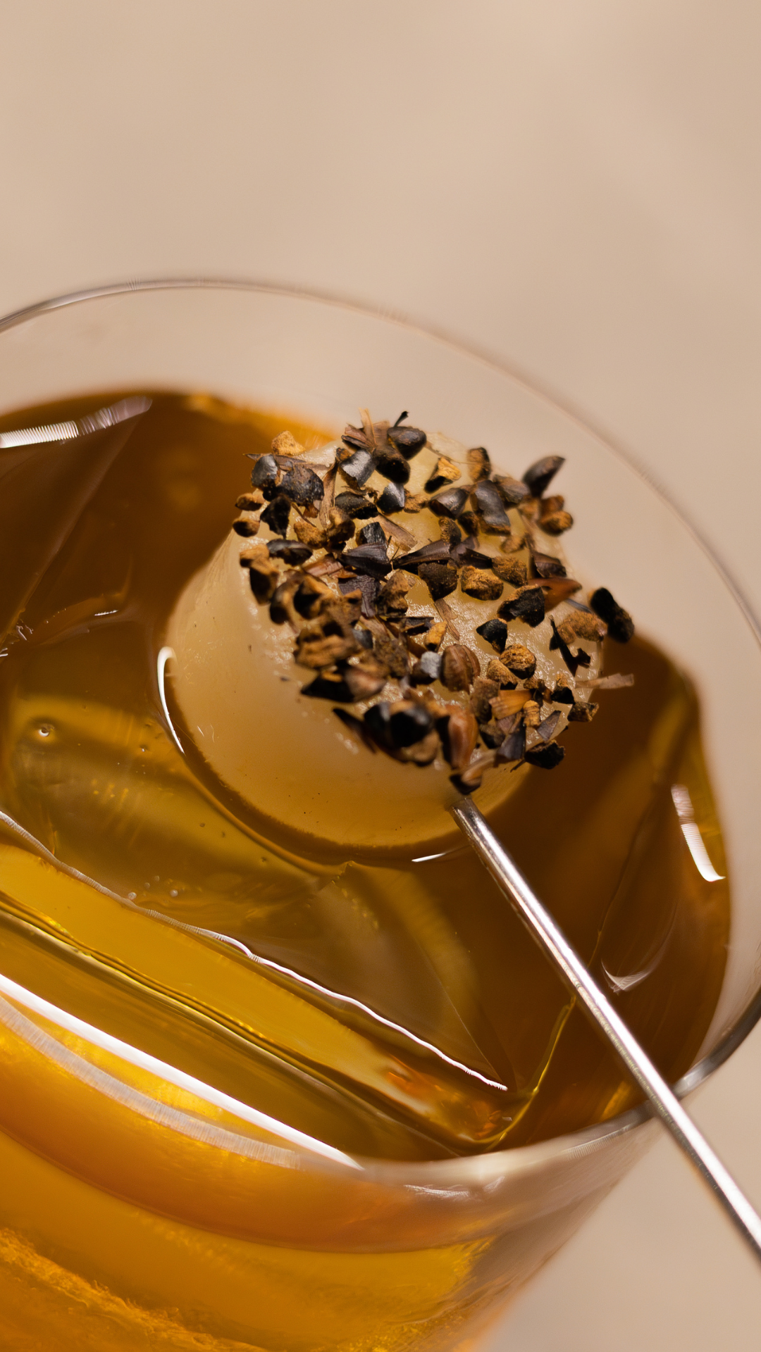 Golden cocktail with chocolate-dipped garnish on a stick in an elegant martini glass.