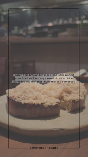 Foie gras on hot milk bread dusted with white powder on a dark plate.