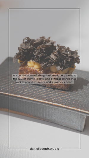 Black truffle toast appetizer presented on a dark serving surface.
