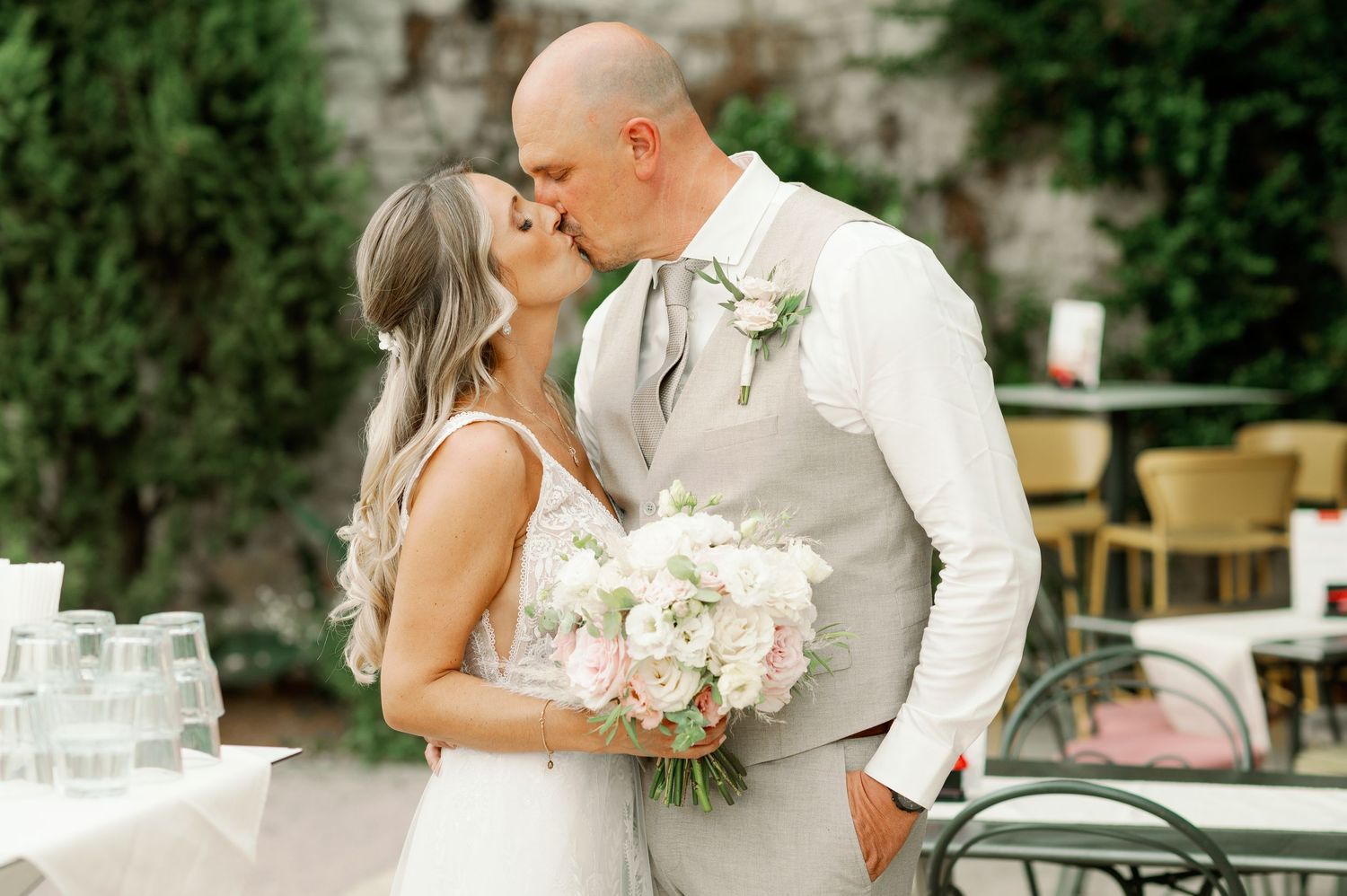 Romantic moment captured during outdoor wedding reception with floral accents.