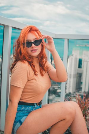 Casual summer style portrait on modern highrise balcony with city view.