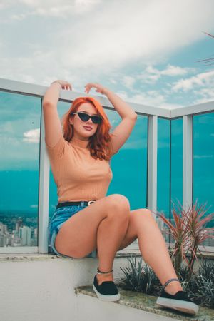 Relaxed rooftop portrait with urban backdrop and casual summer outfit.