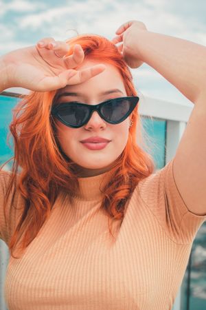 Summer fashion portrait with retro sunglasses against blue sky and cityscape.