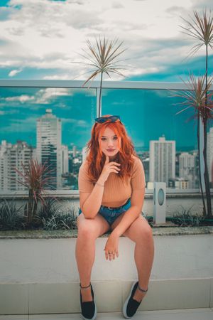 Casual rooftop portrait with palm plants and city skyline in background.