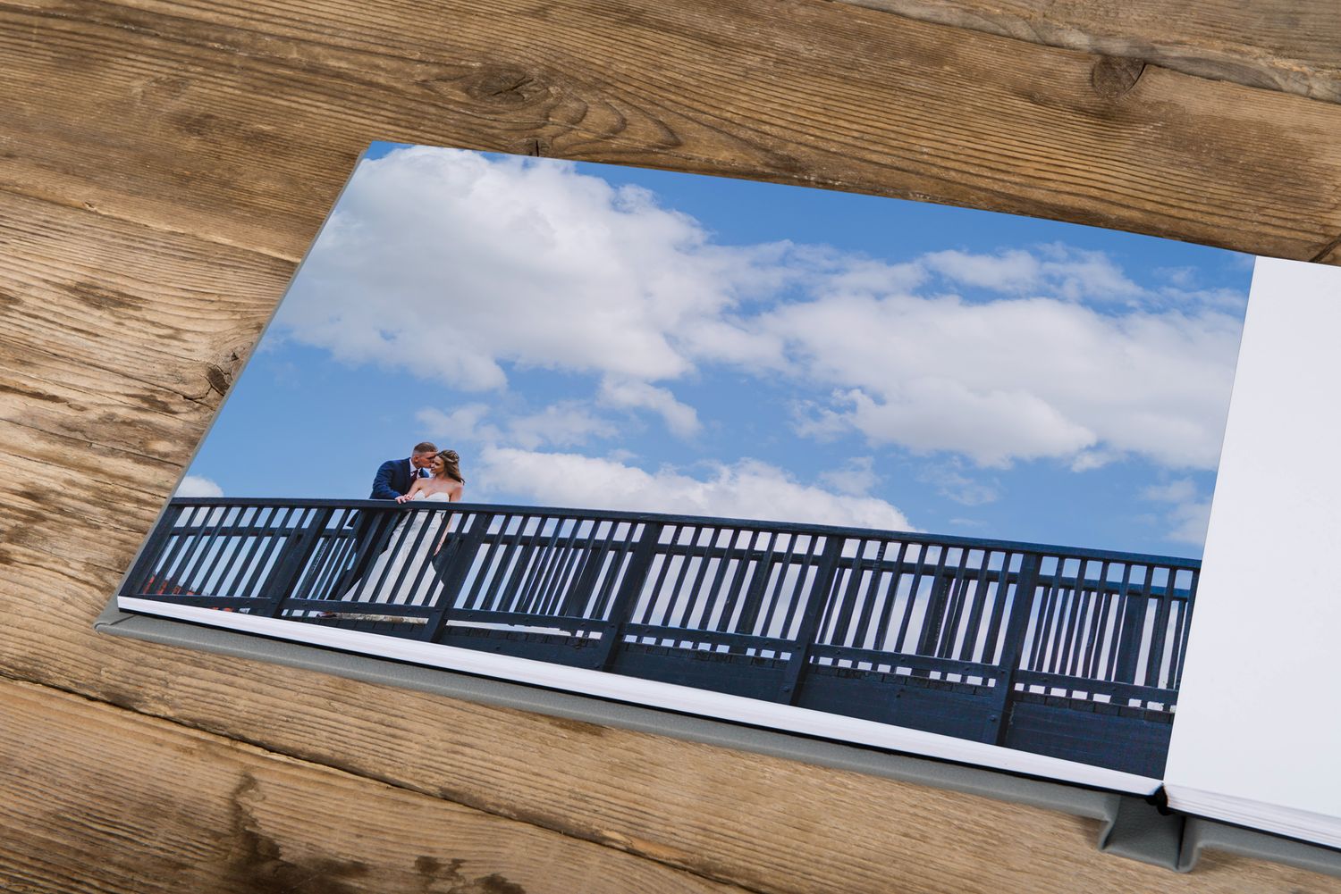 A romantic moment captured on a waterfront balcony against a cloudy blue sky.