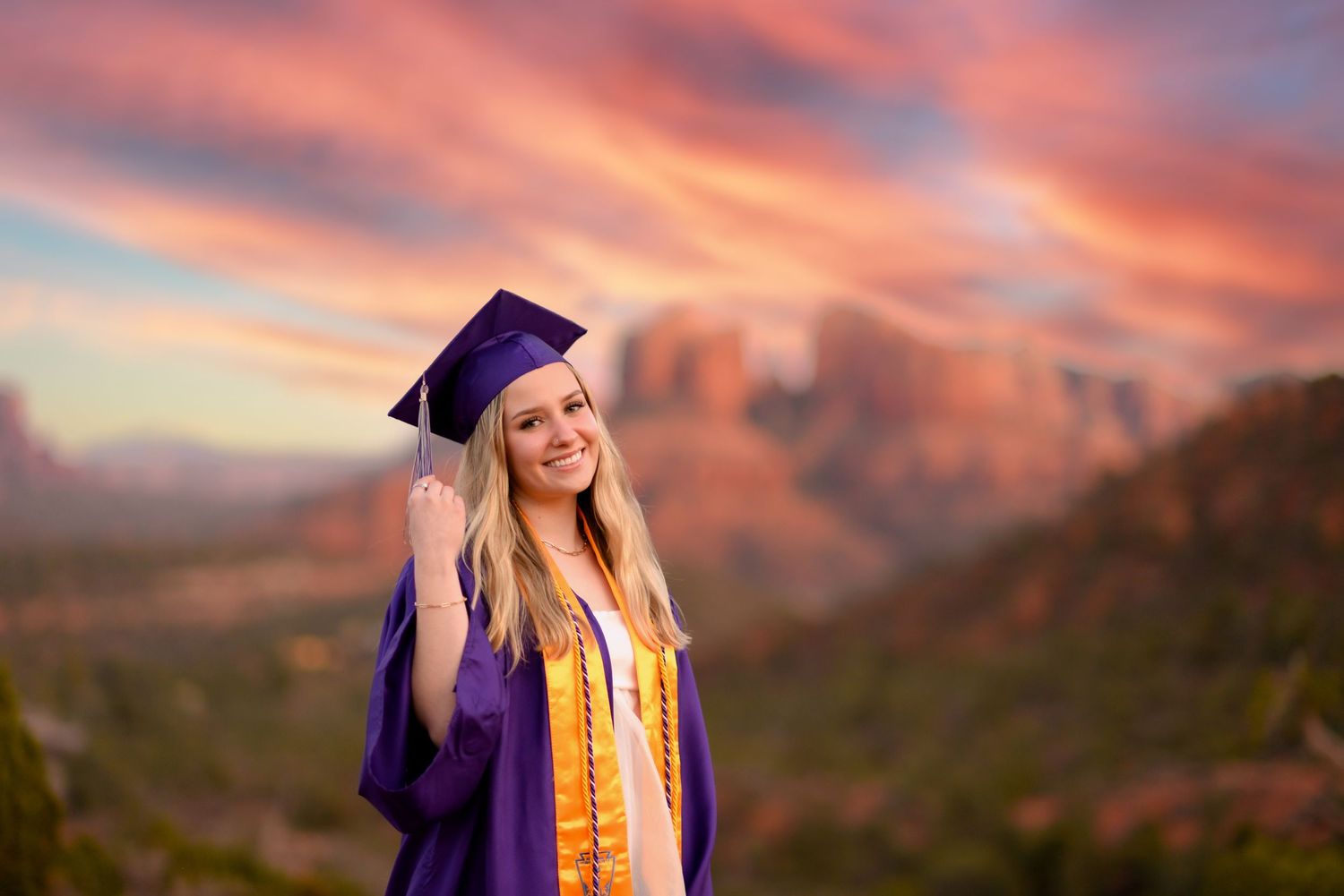 Stunning sunset sky over red rock mountains with vibrant orange and purple clouds. Senior Portrait Photography Sedona Arizona
