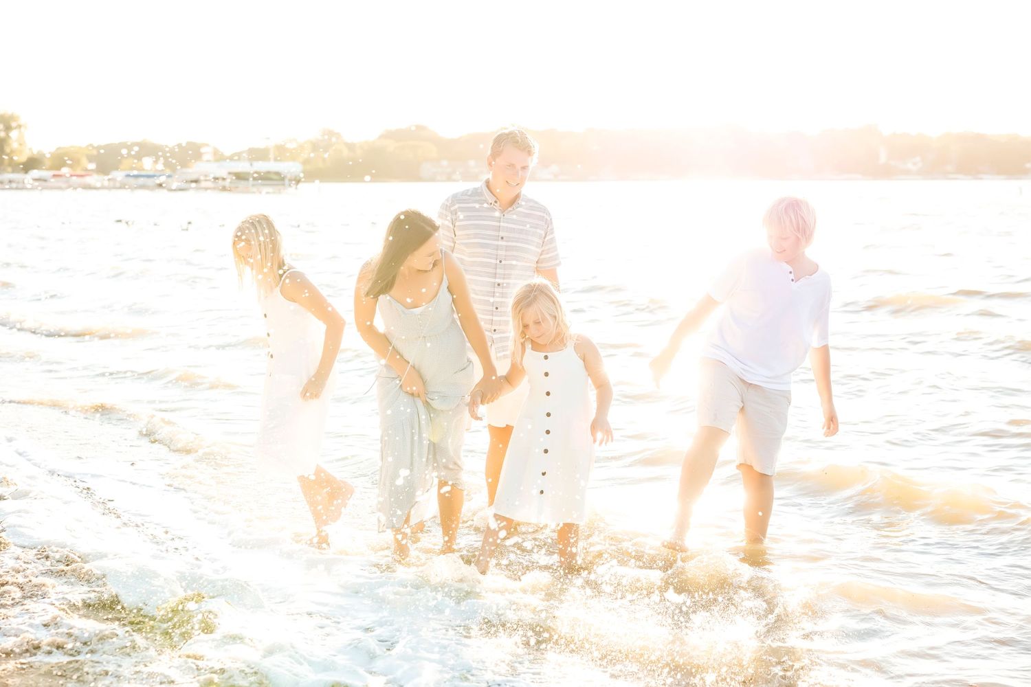 Family splashing and playing in ocean waves at sunset.