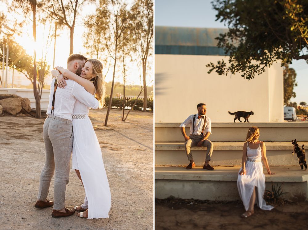 Bride and groom embrace at sunset while sitting apart on steps with a black cat nearby.