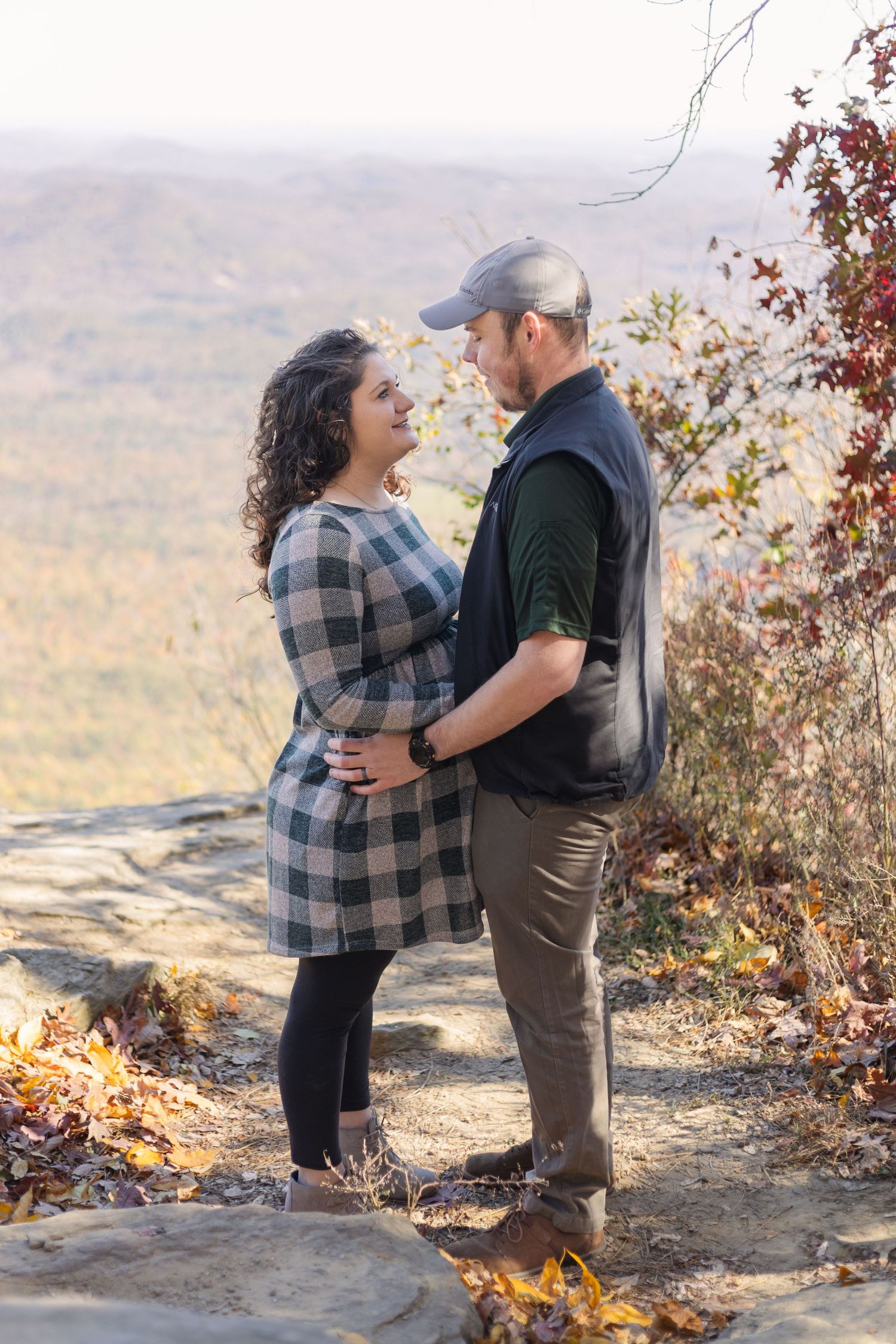 A romantic moment captured on a mountain cliff with fall foliage in the valley below.