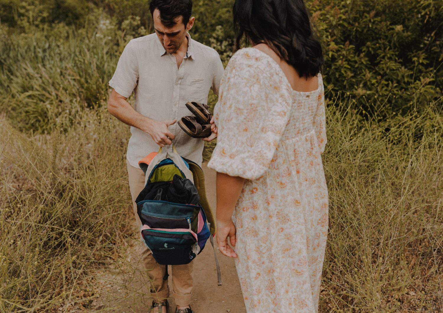 couple hikes up a trail with photographer following behind