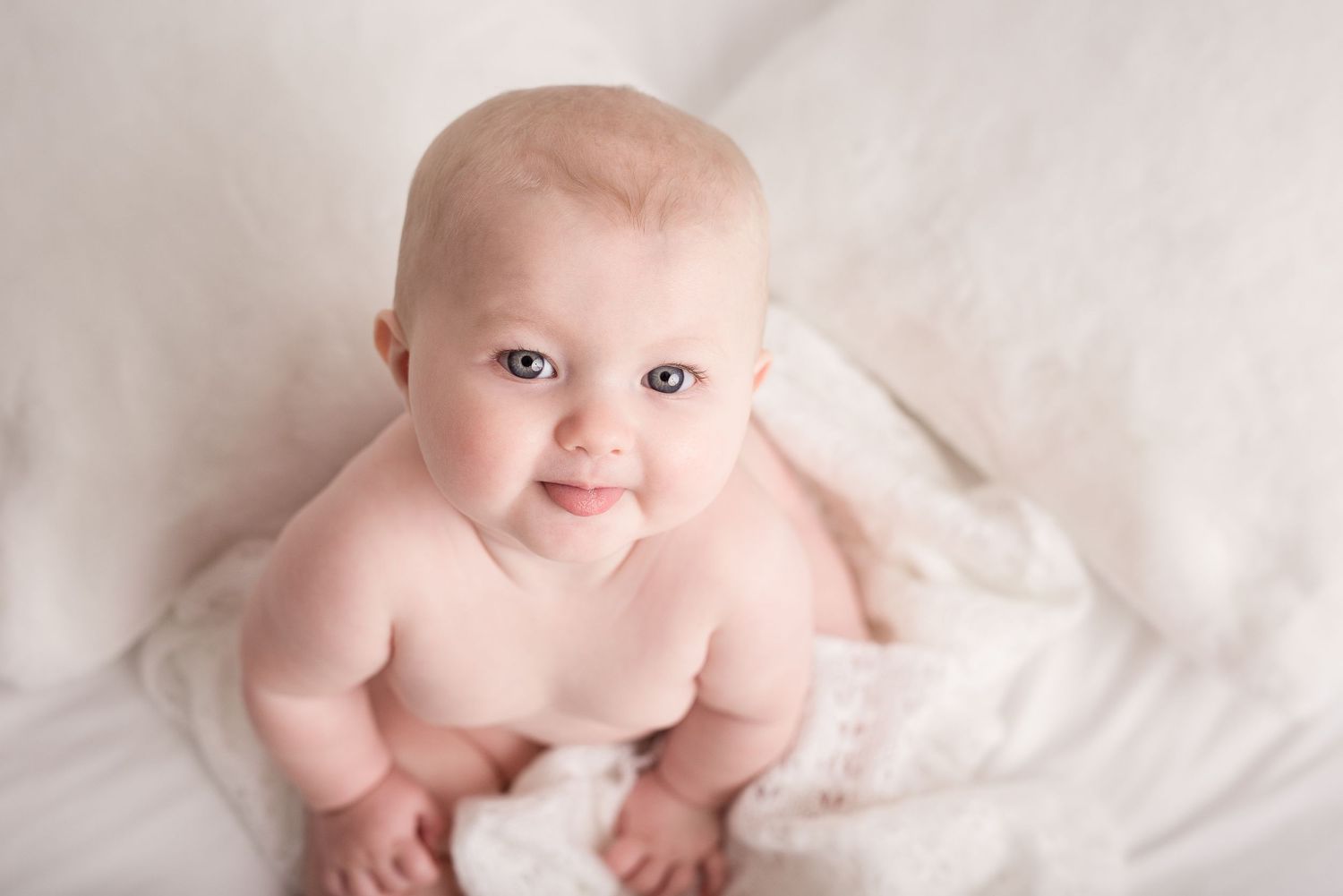 Smiling baby in soft portrait against light colored background.
