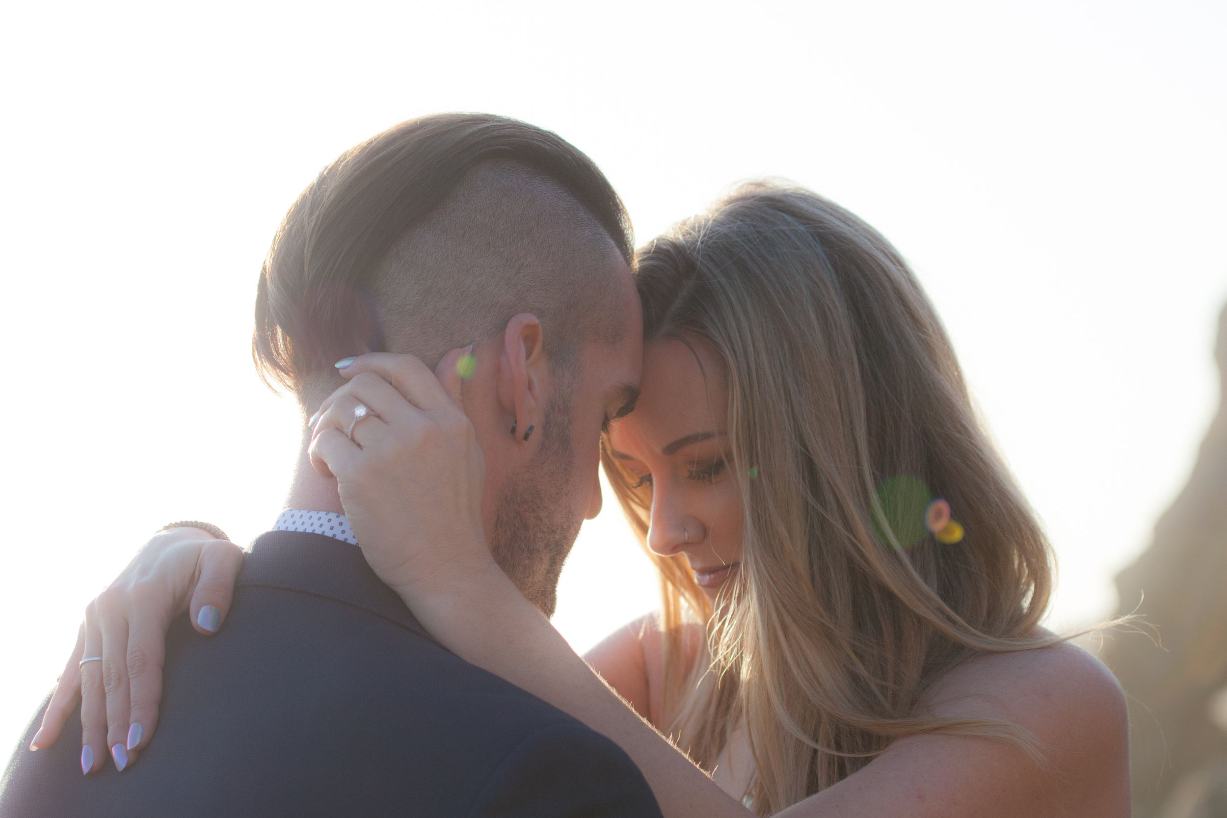 A romantic sunset moment between a couple embracing with warm golden light filtering through.