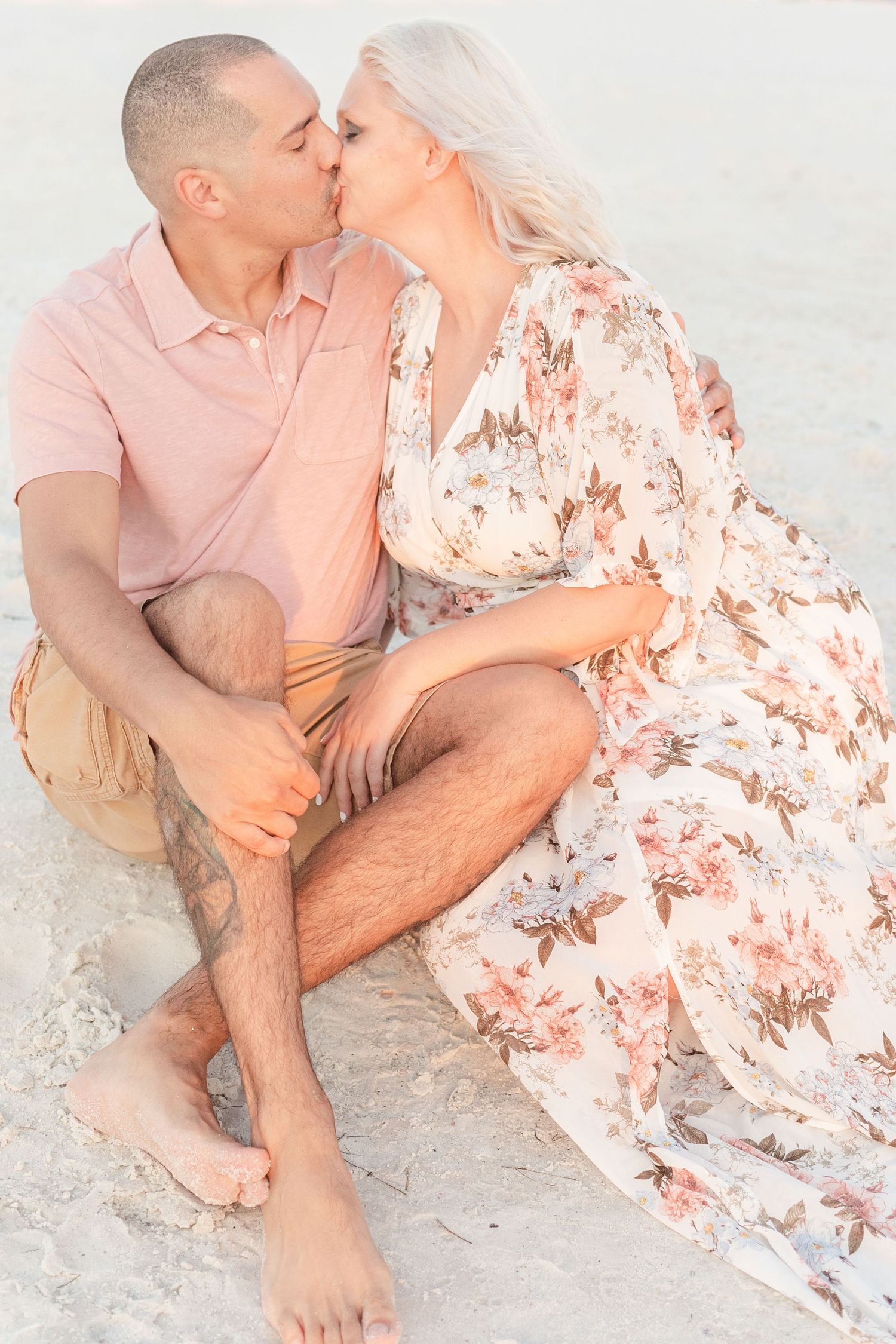 Romantic couple sharing intimate moments while sitting on a sandy beach at sunset.