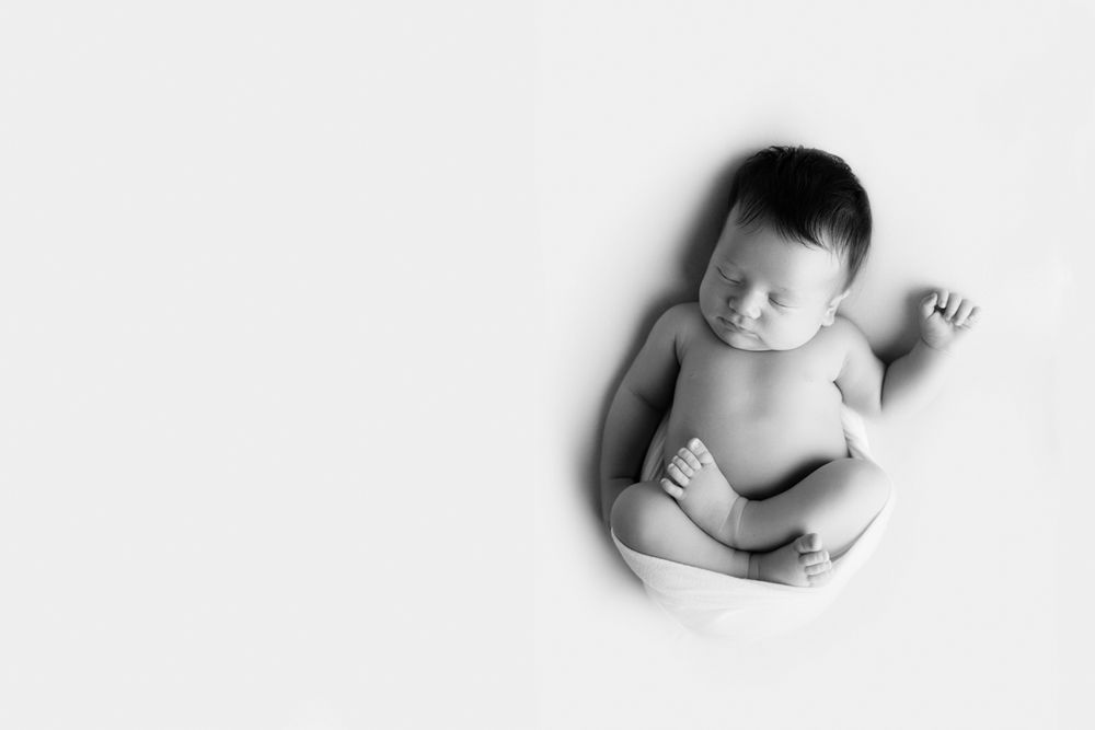Newborn baby girl black and white image with white wrap.