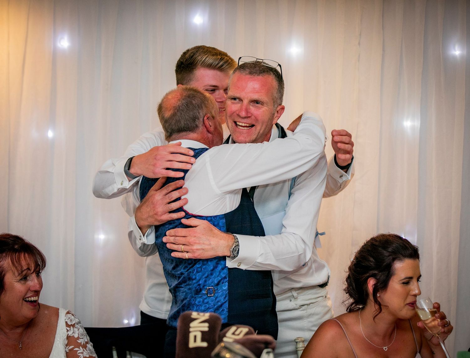 Emotional embraces and celebrations during a wedding reception indoors.