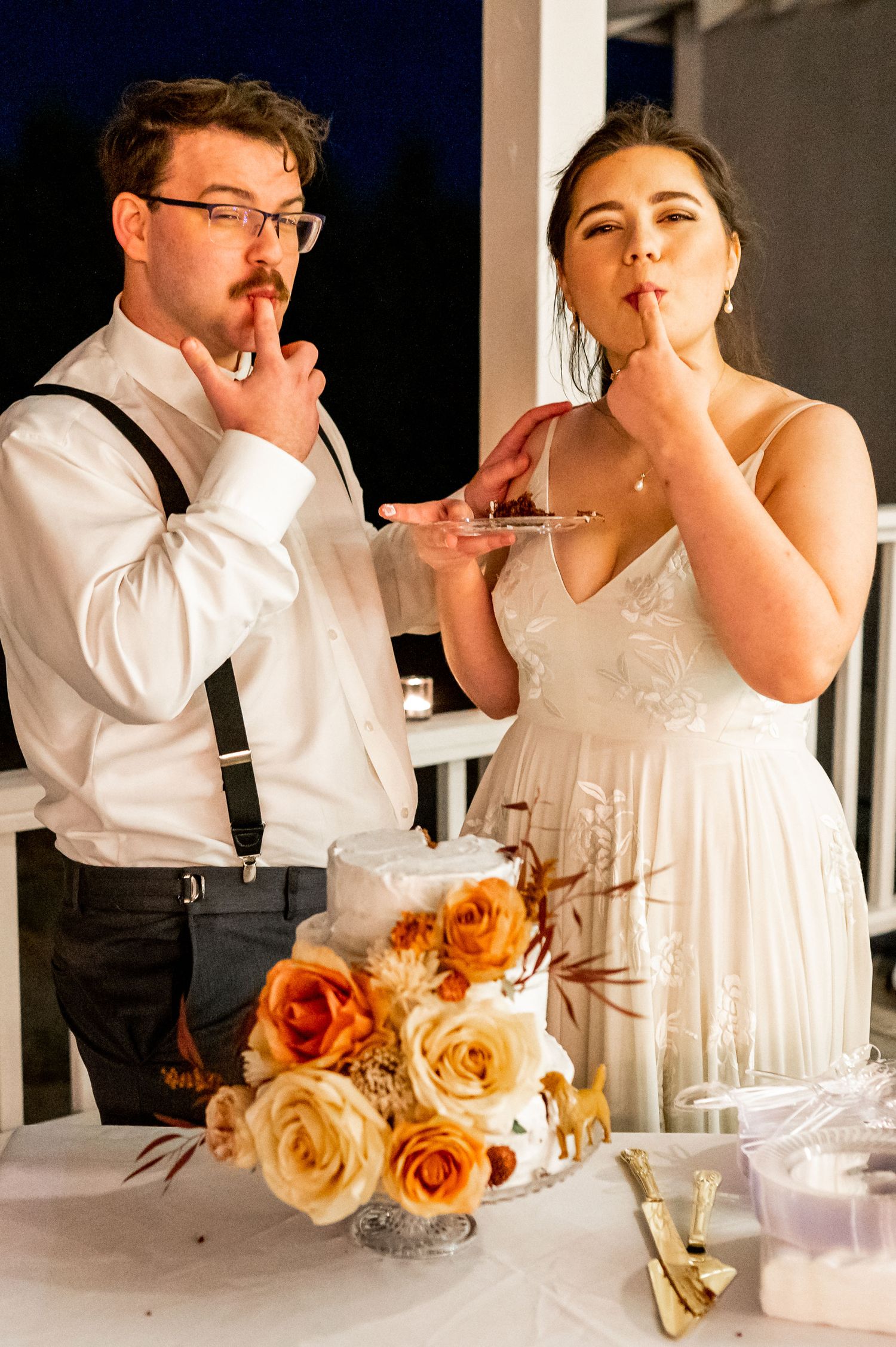 Couple enjoying cake and champagne at their wedding reception table.