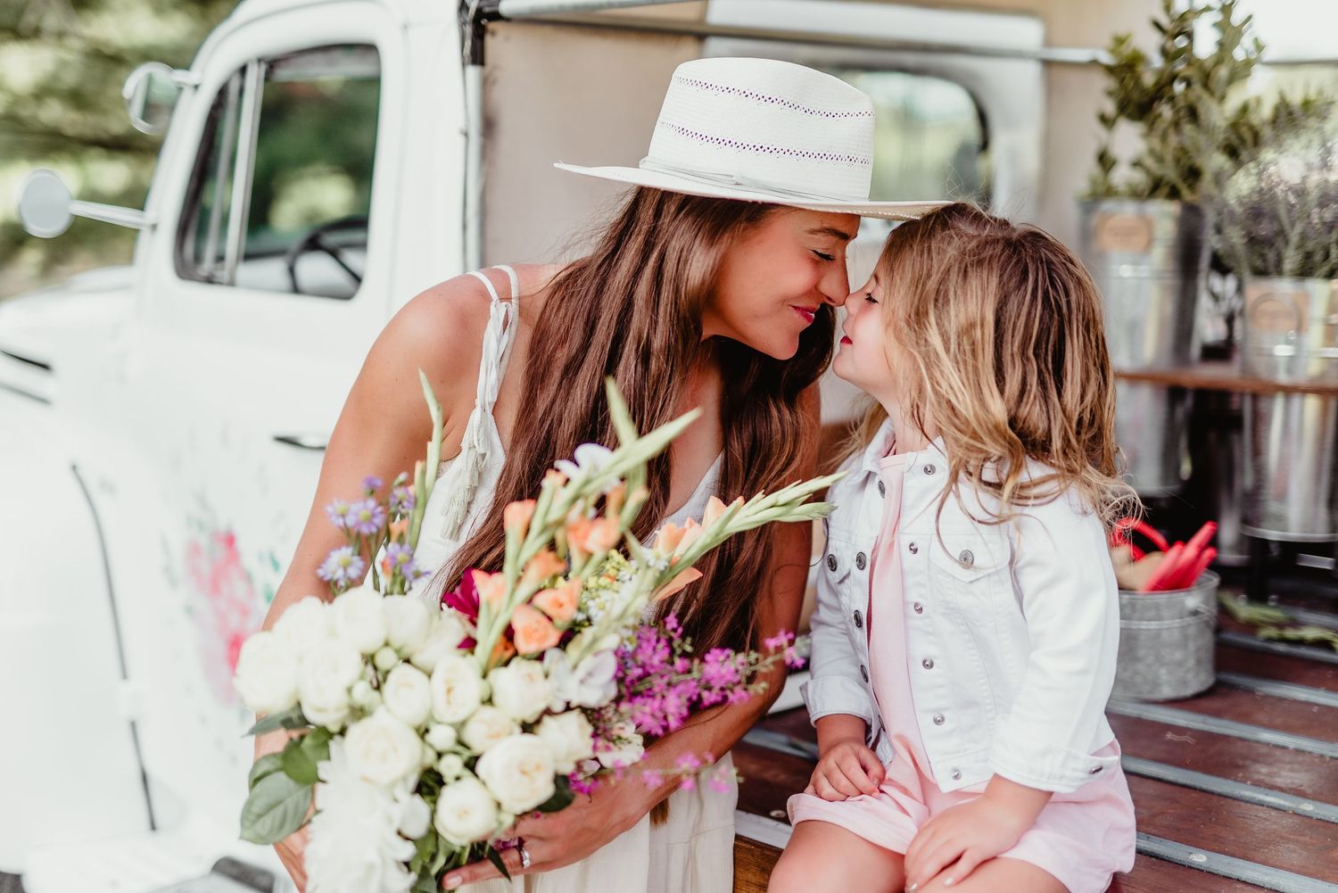A tender moment between parent and child near a vintage white truck with fresh flowers.