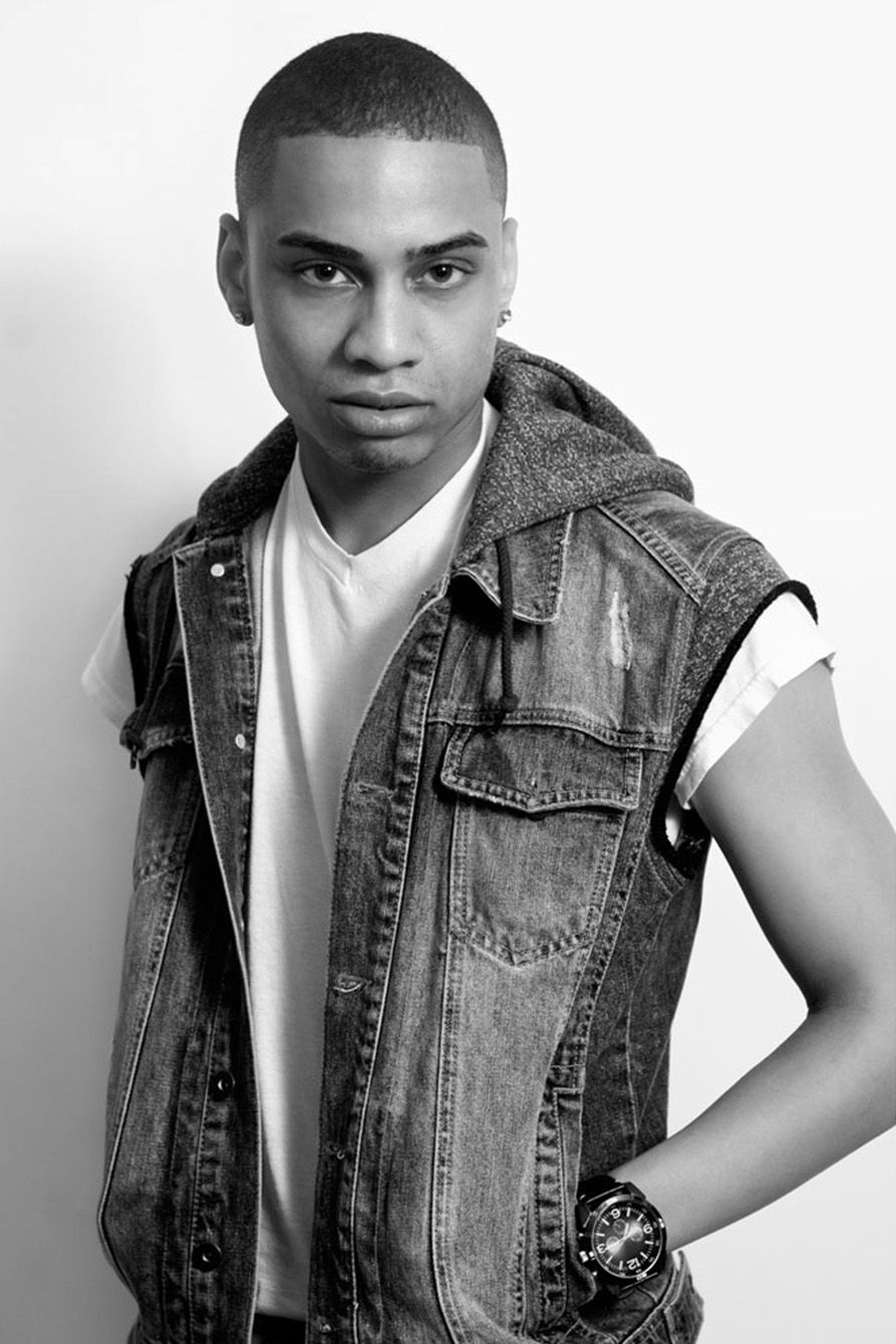 Young man in denim vest and white t-shirt posing in black and white portrait photo.