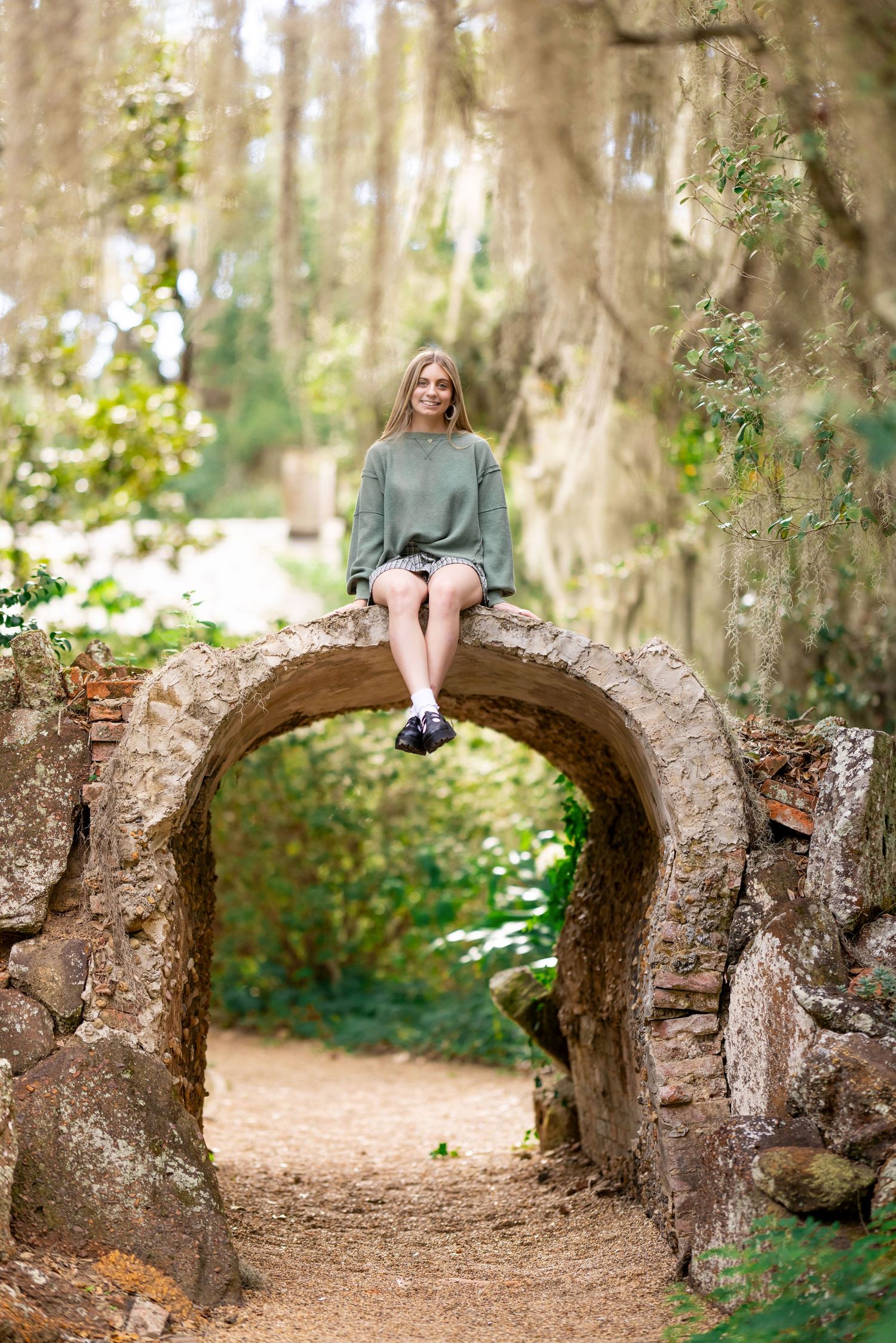 A candid portrait on a stone archway in a mystical forest setting.