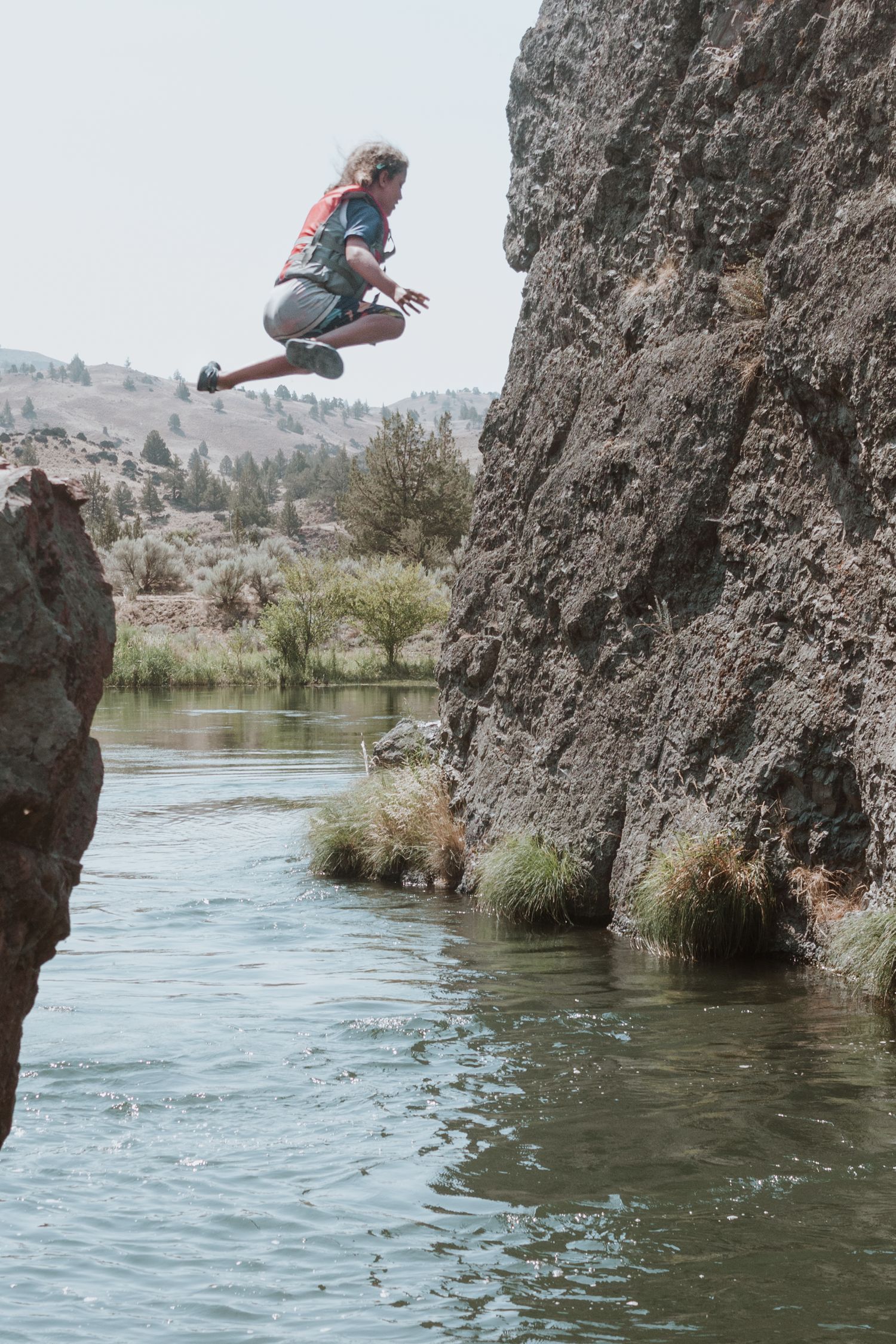 girl jumping off rock into a river