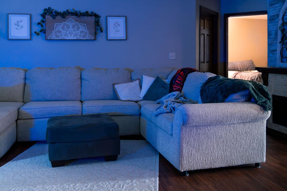 Grey sectional sofa in a dimly lit living room with blue ambient lighting.