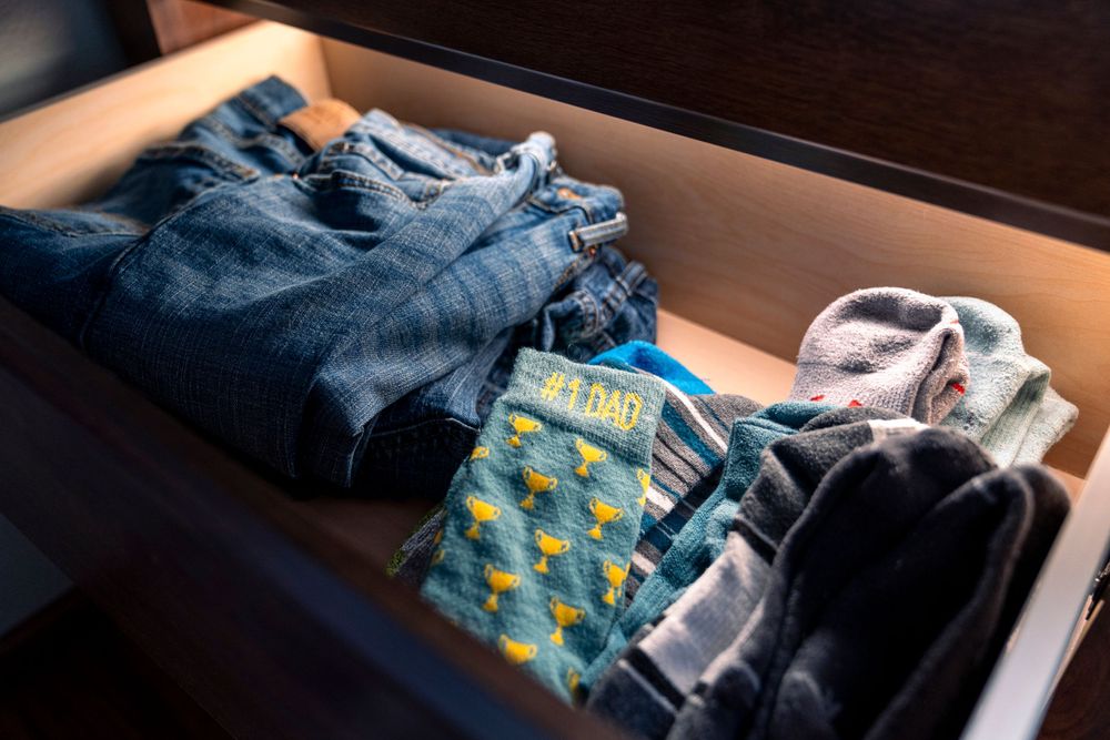 Neatly folded jeans and colorful socks arranged in a drawer.